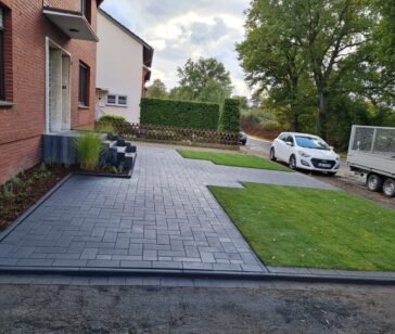 Neu gepflasterte Einfahrt aus anthrazitfarbenem Betonpflaster vor einem Einfamilienhaus
