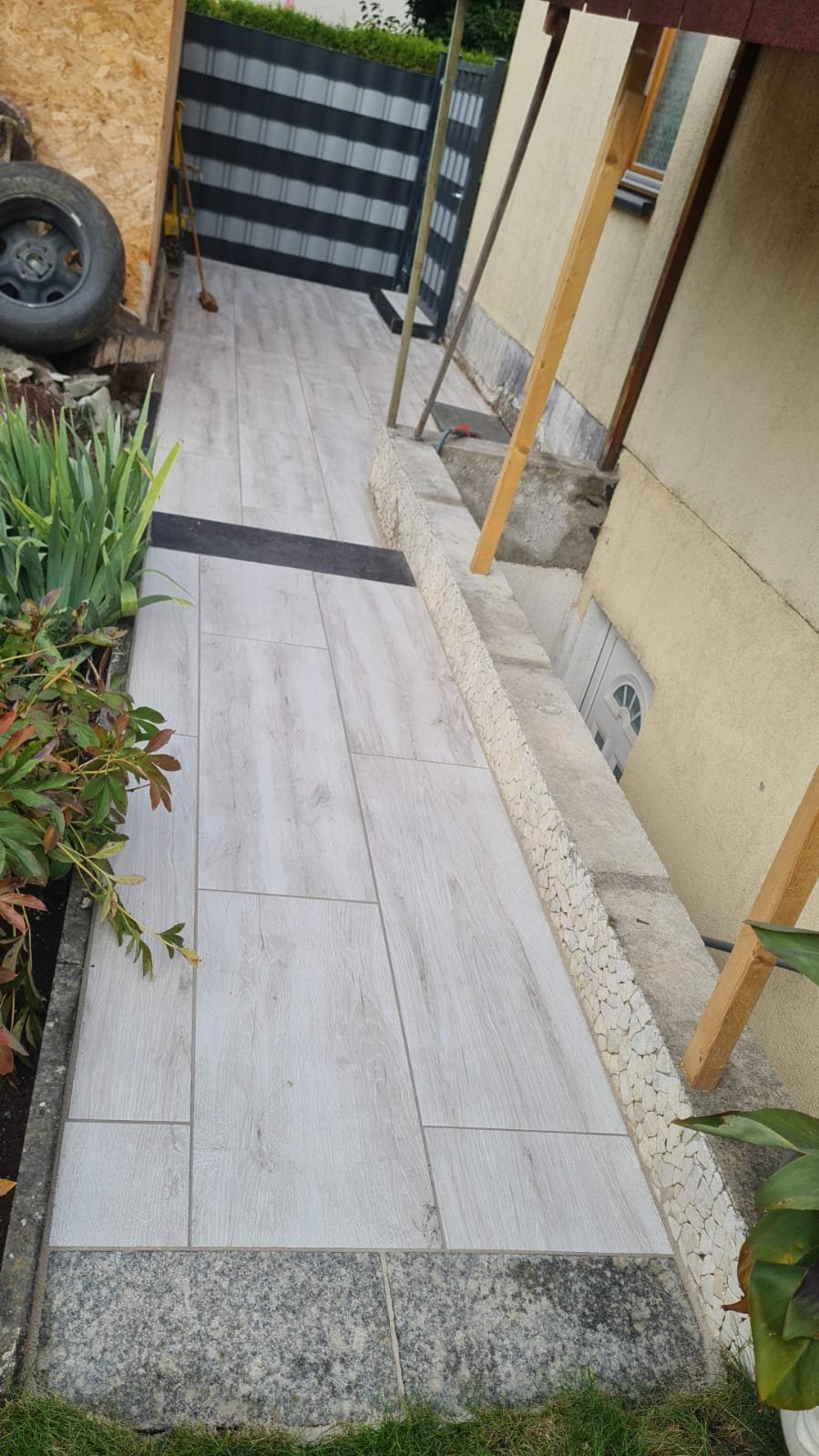 Plattenweg aus grauen Betonplatten entlang einer Hauswand